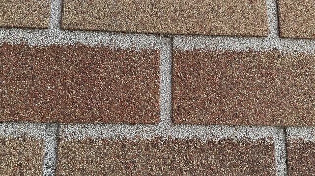 Facade tiles closeup textured brown brick showing granular surface and mortar lines tight framing reveals repeating rectangular.