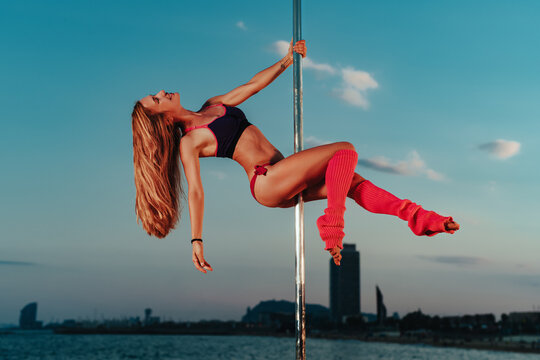 Pole dancer performing on sky background above city skyline