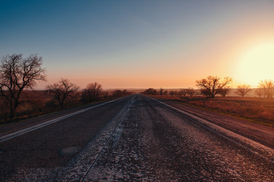 Empty asphalt road leading to horizon at sunset in rural landscape