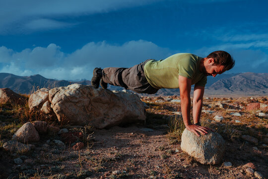 Man doing elevated push ups outdoors using rocks