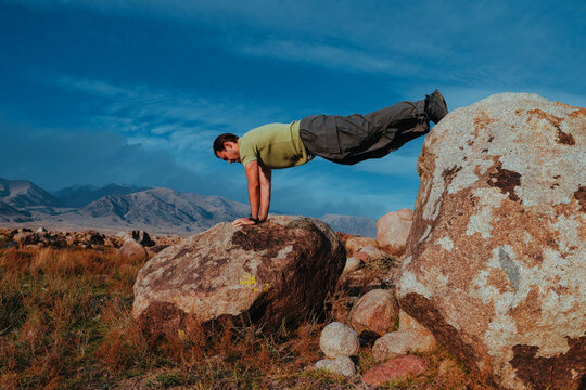 Man doing push ups on rocks on wild nature