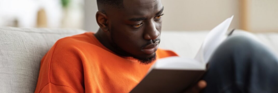 Man reading book on sofa in living room interior space