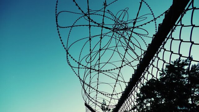 Rusty barbed wire on fence with dramatic lighting