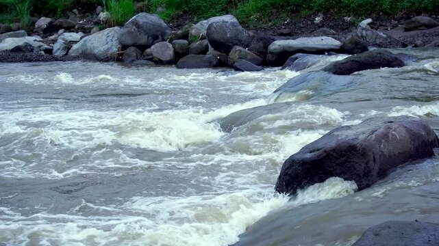 Fast flowing river water rushing over volcanic boulders in the Mount Kelud lahar path, Indonesia, Southeast Asia during late afternoon dusk.