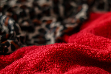 Red teddy fleece fabric folds with blurred leopard print textile background. Soft textures © LadyLensArt 