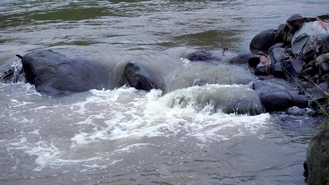 Fast flowing turbulent river water rushing over volcanic rocks in the Mount Kelud cold lava lahar path, Indonesia.