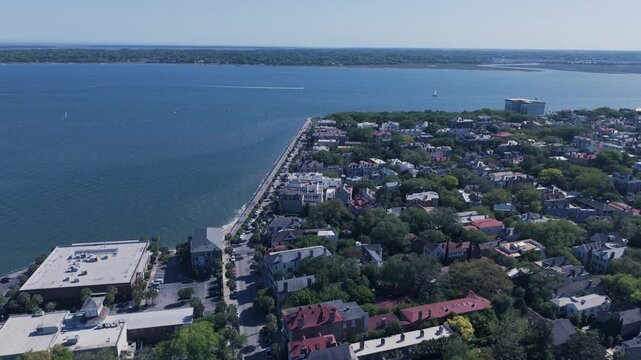 Aerial-Flying over the Charleston High Battery seawall with promenade on top passing residential area and approaching the Ashley River with lone small boat cruising up the river