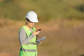 Fototapeta premium Woman construction engineer checking data on smartphone and tablet