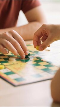 Teenagers playing board game together at table indoors, friendship and social activity concept, vertical video close up.