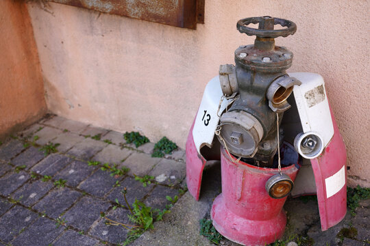 Vintage red fire hydrant with damaged protective casing on a street in Thiers, France