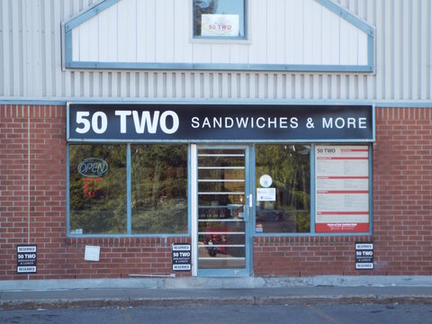 
Nepean, Ontario, Canada &ndash; July 27, 2025: The "50 Two Sandwiches & More" storefront features a black sign and red menu displays on a brick building at 52 Antares Drive.