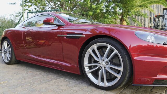 Maspalomas, Las Palmas, Canary Islands, Spain - April 13, 2024 - A bright red luxury sports car showcasing its sleek design and alloy wheel, parked outside on a paved driveway