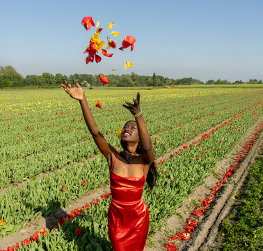 Joyful Young Woman Tossing Tulip Petals in Colorful Flower Field