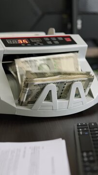 Closeup shot of banknote counting machine with Indian rupee (INR) money. Automatic currency counter equipment processing 500 rupees with Mahatma Gandhi portrait. Finance and banking industry in India.