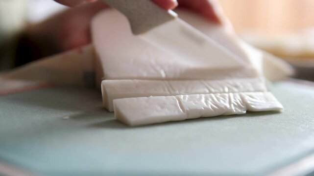 A festive cheese assortment is being sliced and arranged for a holiday table. Close-up of white, sheep, and goat cheeses being cut and served, highlighting texture, freshness, and simple elegant.