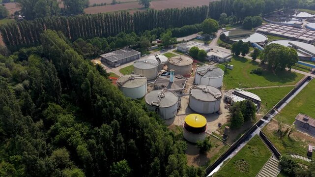 Aerial View of Industrial Site: An elevated view capturing the expansive layout of a plant, bordered by lush greenery, illustrating the interface of development and the environment.