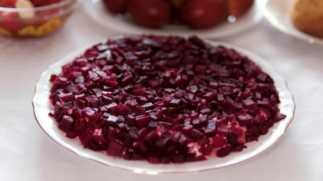 A modern version of Ukrainian shuba salad served on a white plate with beetroot cut into cubes instead of grated layers. deconstructed herring under fur coat salad with a fresh presentation style.