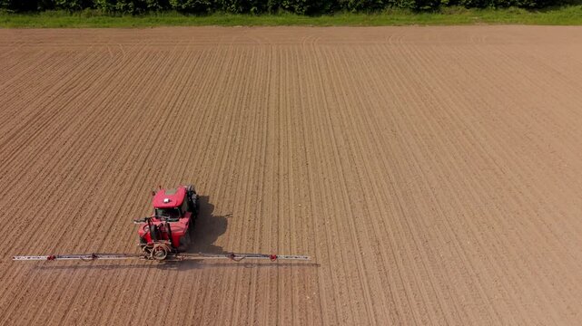 Tractor Plowing Field: A red tractor plows a vast, dry field, leaving straight furrows in its wake under a clear sky.