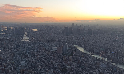 Obraz premium Aerial view of Tokyo at sunset from Tokyo Skytree, featuring dense urban skyline and rivers reflecting warm evening light