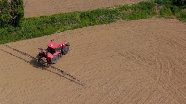 Red tractor plowing field: A powerful red tractor navigates a vast, newly plowed field, preparing the earth for its next cultivation, symbolizing agricultural progress.