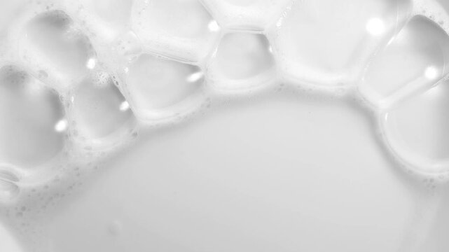 Foam bubbles background. Moving Soap foam popping bubble, white backdrop. Soap sud macro structure. Soap foam close-up. Clean, cleaning concept, laundry, shower. Slow motion 
