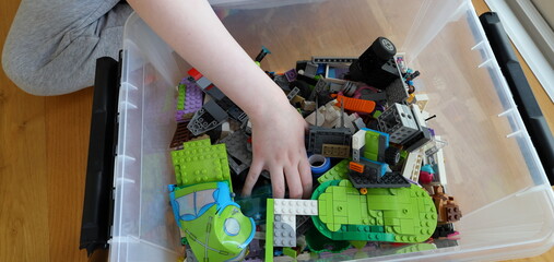 Naklejka premium Kid playing with Lego. Assembly bricks or blocks in plastic. Hand visible.