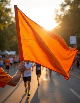 Hand holding orange flag at sunset during marathon race
