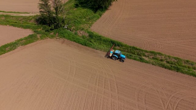 Agricultural Automation: An aerial shot captures a tractor working on a farm, its wheels leaving a patterned imprint on the soil, symbolizing the evolution of agriculture. 