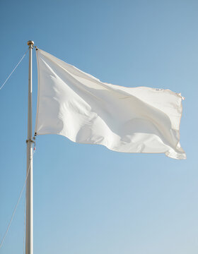 White flag waving on a flagpole against a clear blue sky