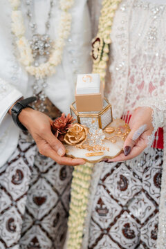 "The Sacred Exchange: Traditional Indonesian Wedding Ring Presentation in Batik Attire"