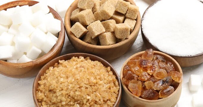 Different types of sugar on white wooden table, spinning