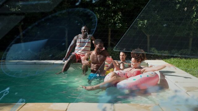 Pool group starting toast as man at edge reaching raising cups clinking relaxing on pink float