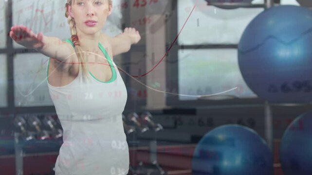 Vertical video: Panning up woman in tank lifting arms, twisting in gym blue mat overlay for balance
