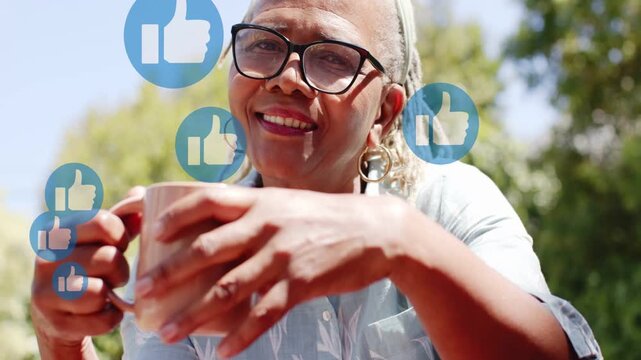 Vertical video: Holding mug, senior woman wearing blue shirt laughing outdoors as like icons rising