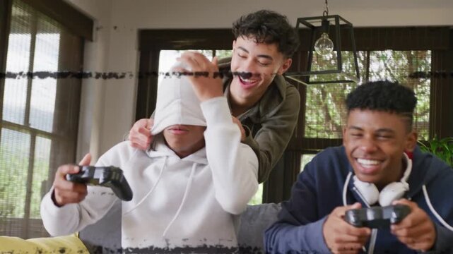 3 boys gaming; standing boy pulling hoodie to tease, controllers cheering win, blue lines glitching