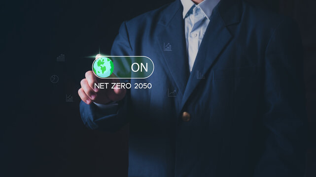 Businessman touching virtual toggle switch for Net Zero 2050 goal. Concept of global sustainability, ESG corporate responsibility, carbon neutrality, and environmental protection for green future.