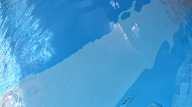 Abstract underwater view of a swimming pool floor with soft blue gradients, rippling light, and calm resort ambience, creating a clean luxury water background.