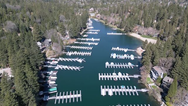 op view aerial drone footage of Lake Arrowhead marina with docks and empty boat slips. Top-down aerial video of marina docks and empty boat slips on Lake Arrowhead surrounded by forest and lakeside 