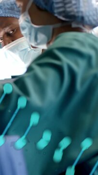 Gloved hands entering frame, masked staff adjusting tools for surgery, turquoise overlay obscuring