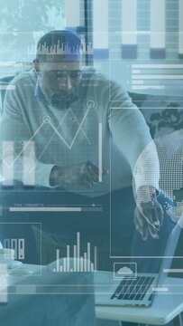 Vertical video: Man viewing laptop, leaning in tapping HUD globe and charts, analyzing finance data