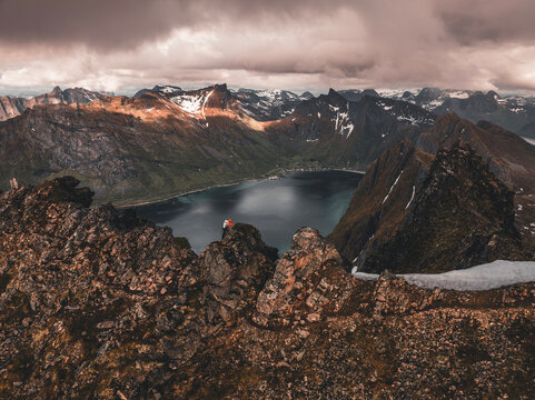 Hiker on Hesten mountain overlooking fjord landscape on Senja island in Norway