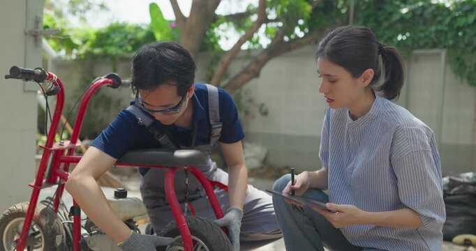 Startup founder and engineer inspect, document and test a minibike prototype outdoors at small business workshop during product development, repair review and SME innovation.
