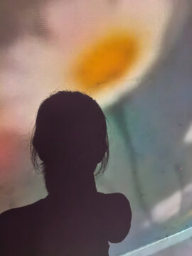 Artistic silhouette of a woman against a blurry colorful flower projection background