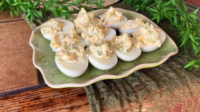 Plate of deviled eggs on a rustic table, styled as a homemade appetizer with creamy filling, herbs, and cozy kitchen presentation.