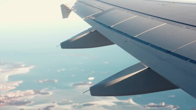 Vintage film-look airplane wing view over sunlit islands and blue sea, capturing a warm sunset travel vibe with dreamy coastal scenery from above.