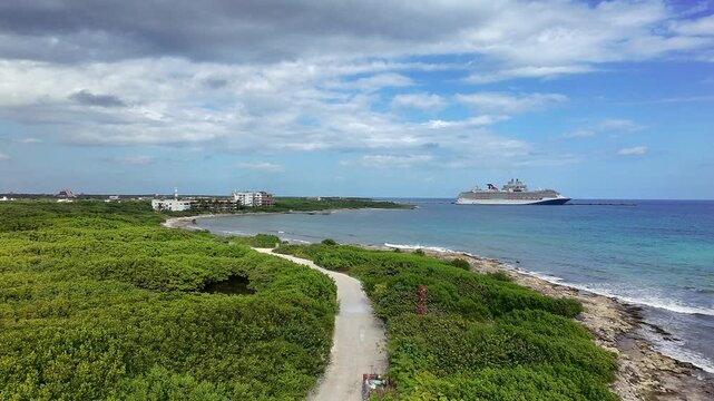 Aerial drone view of Mahahual coastline in Costa Maya, Mexico with cruise ship offshore, turquoise Caribbean waters, tropical vegetation and scenic shoreline.