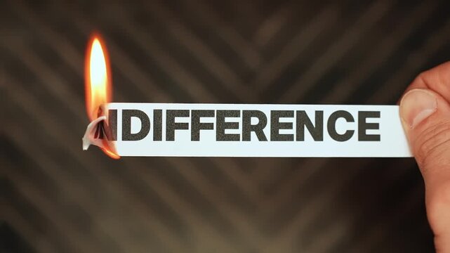 Burning &ldquo;indifference&rdquo; label held by hand, symbolizing empathy, compassion, emotional connection, and choosing care, kindness, and human concern over apathy.