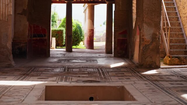 Interior of an ancient Pompeii house with geometric mosaic flooring, central basin, and sunlit columns revealing preserved Roman domestic architecture.