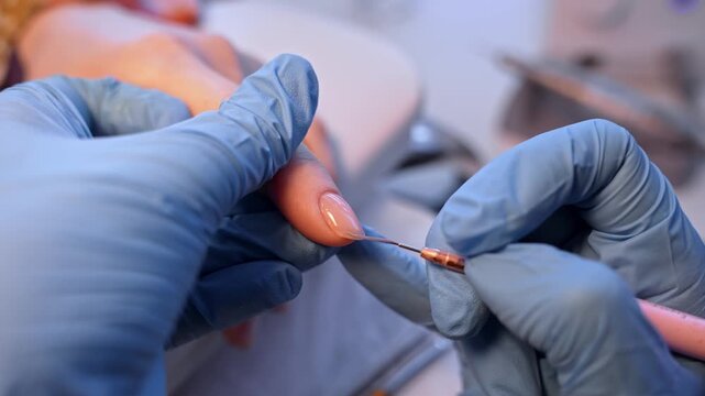 Precision salon close-up of a nail technician refining a neutral glossy manicure with a micro liner brush, showing delicate edge correction and luxury beauty detailing.