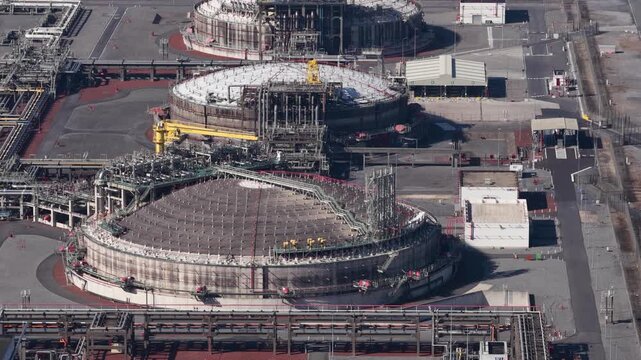 High angle aerial perspective showing large liquefied natural gas storage tanks and intricate piping systems at a modern energy production and distribution facility for global fuel supply